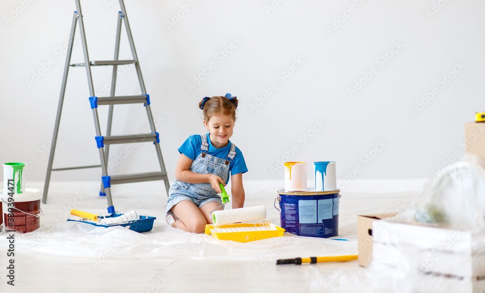 renovation in apartment. Happy child girl  paints wall .