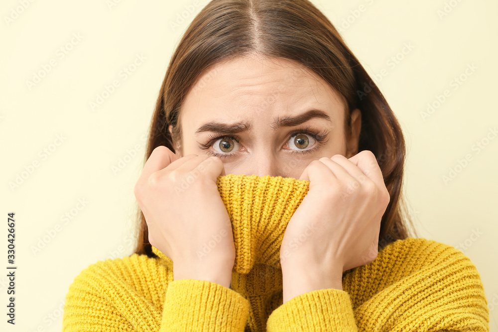 Scared young woman on light background