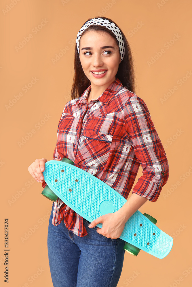 Stylish young woman with skateboard on color background