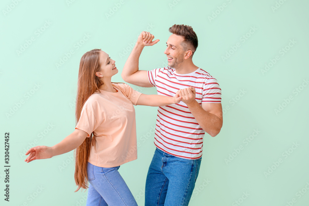 Happy young couple dancing against color background