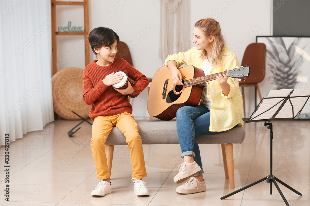 Private music teacher giving lessons to little boy at home