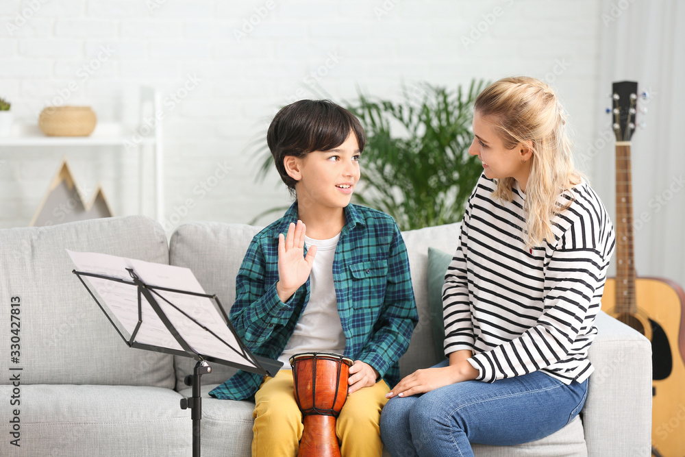 Private music teacher giving lessons to little boy at home