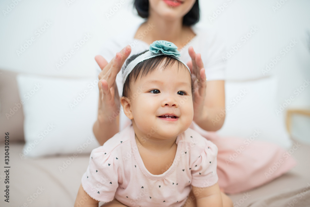 小女孩坐在家里的床上。一位年轻的母亲紧紧抓住一个有头发的女儿