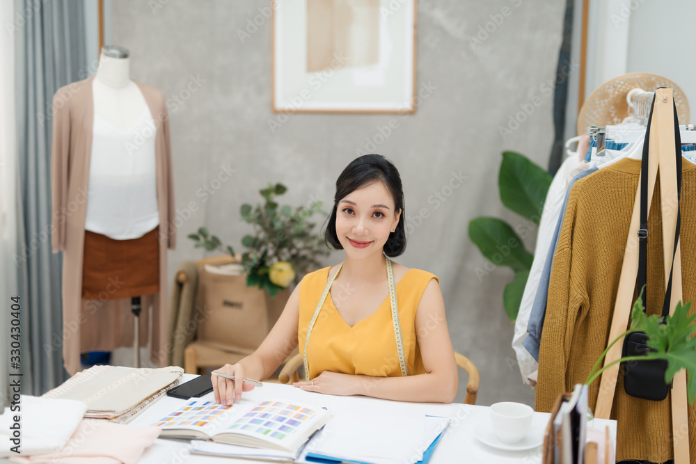 Portrait of a young fashion designer working on her atelier