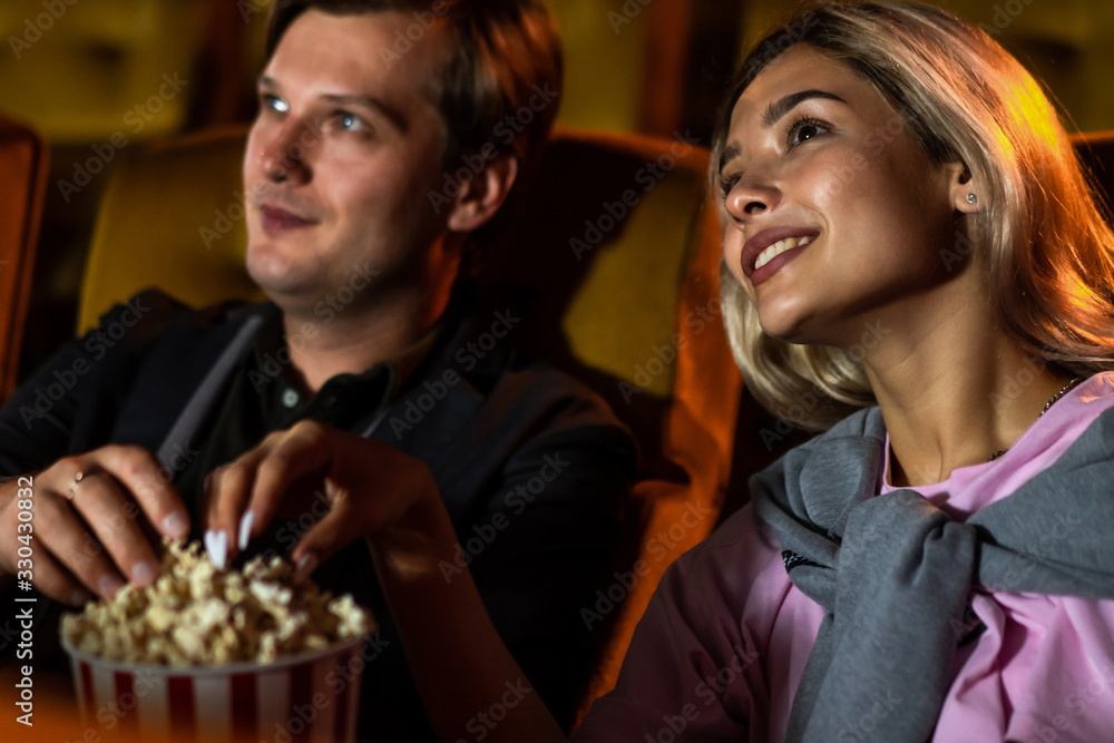 Caucasian lover enjoying to watch movie and eating popcorn together in the cinema