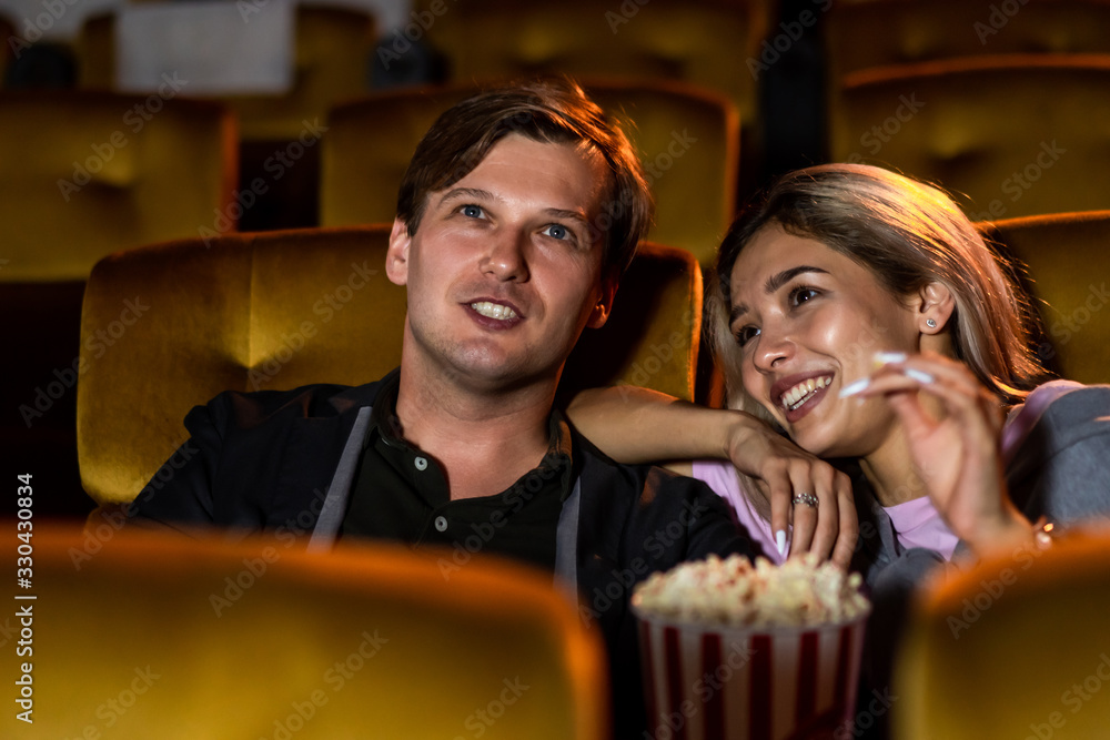 Caucasian lover enjoying to watch movie and eating popcorn together in the cinema