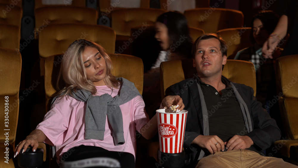 Audience walking to seats in the movie theater, watching film and eating popcorn.