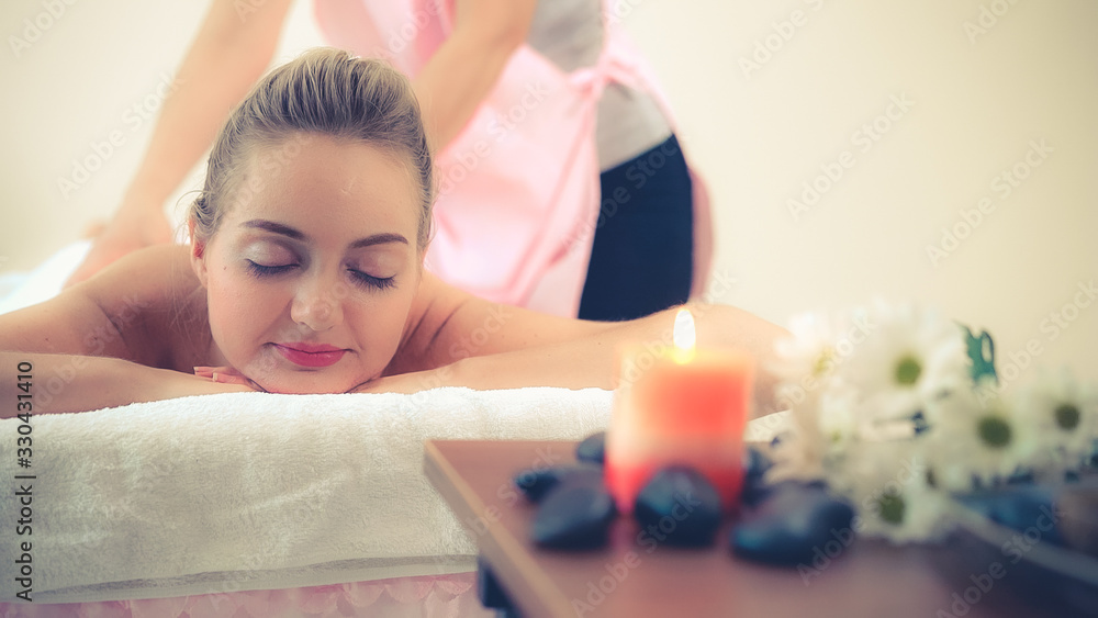 Relaxed woman getting back massage in luxury spa with professional massage therapist. Wellness, heal