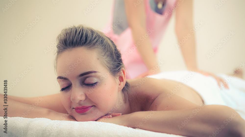 Relaxed woman getting back massage in luxury spa with professional massage therapist. Wellness, heal