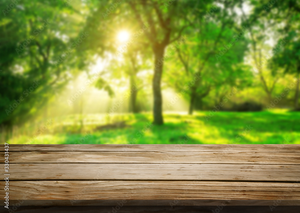 Brown wood table in green blur nature background of trees and grass in the park with empty copy spac