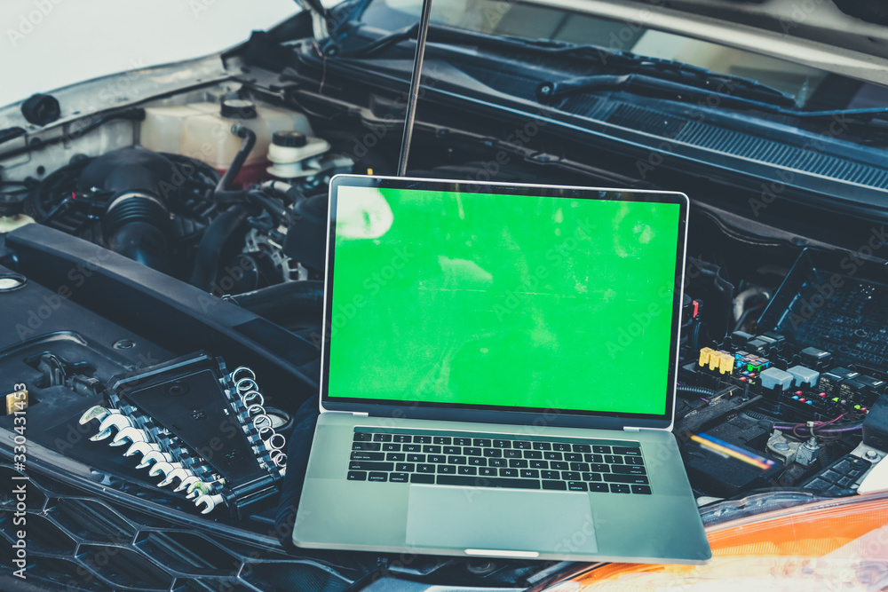 Laptop computer on car hood for engine diagnostic. Car garage repair service concept.