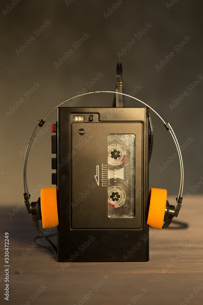 Old portable cassette player and headphones on a abstract background. Vintage advertisement style