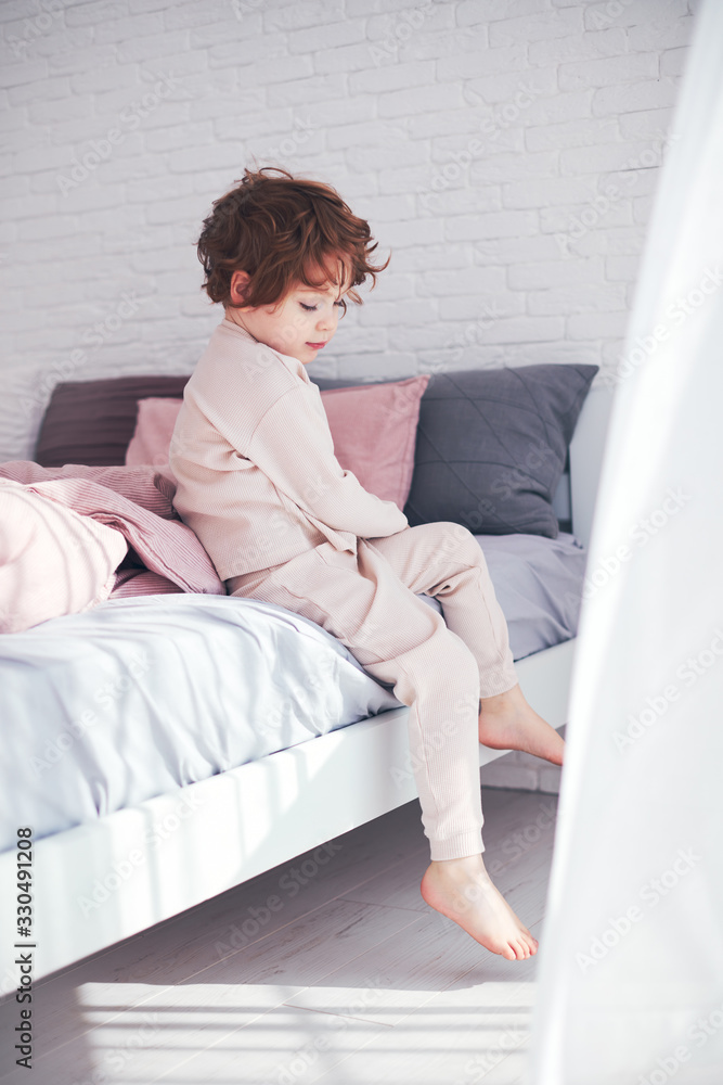 cute redhead baby boy getting up in the morning at sunny bedroom