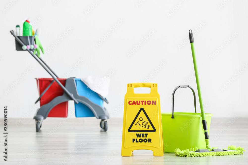 Caution sign with cleaning supplies indoors