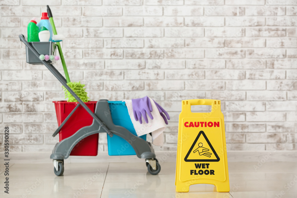 Caution sign with cleaning supplies indoors