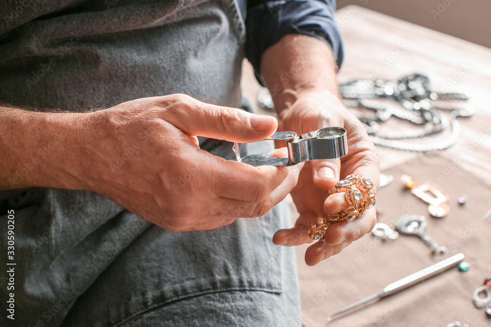 Jeweller examining adornment in workshop, closeup