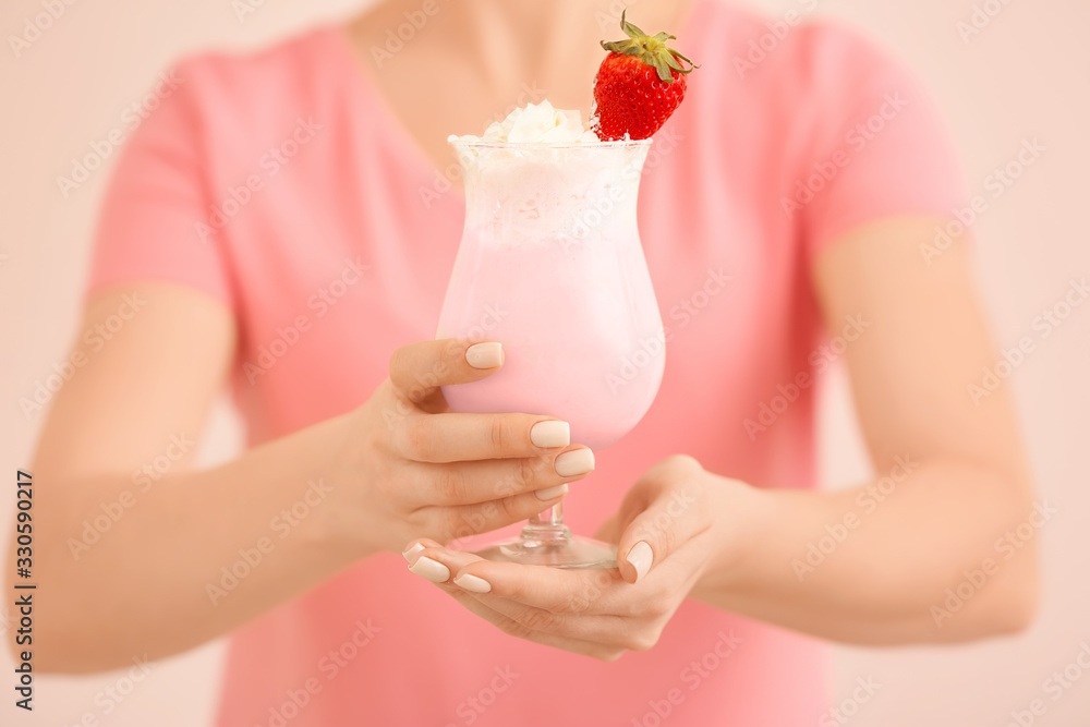 Woman with glass of tasty milkshake on color background, closeup