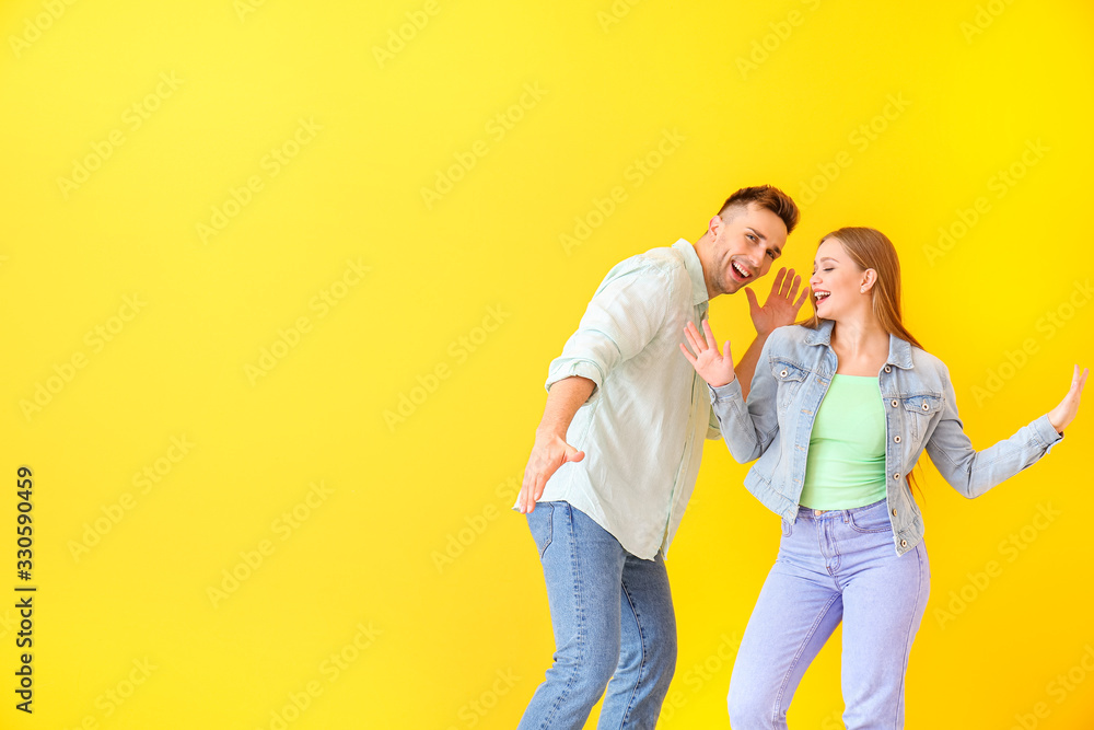 Happy young couple dancing against color background