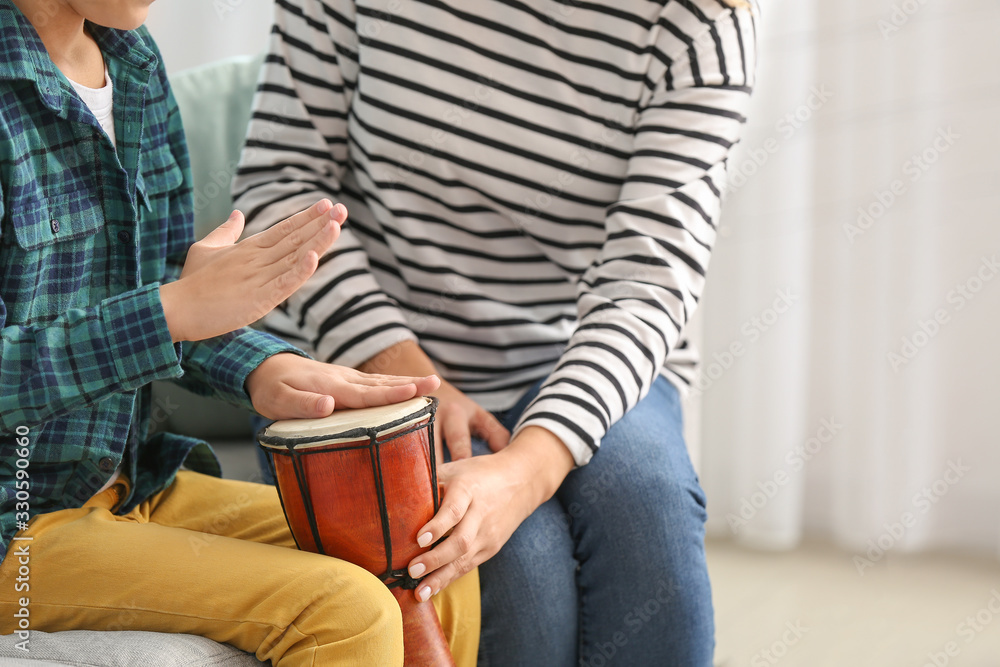 Private music teacher giving lessons to little boy at home