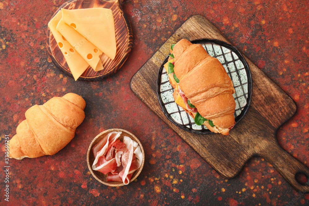 Tasty croissant sandwich with ingredients on plate