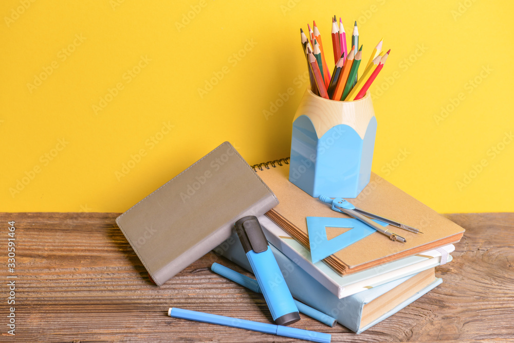 Set of school supplies on table against color background