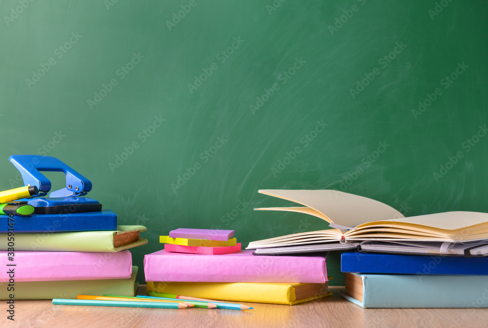 Set of school supplies on table near blackboard