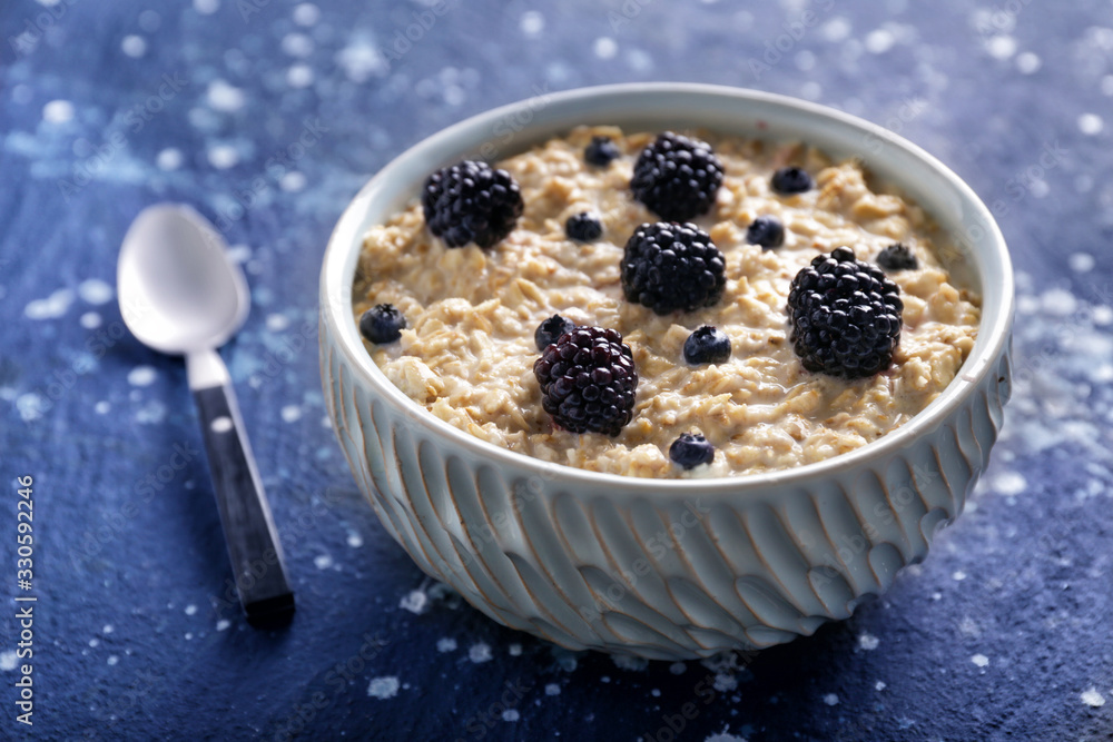 Bowl with tasty sweet oatmeal on color background