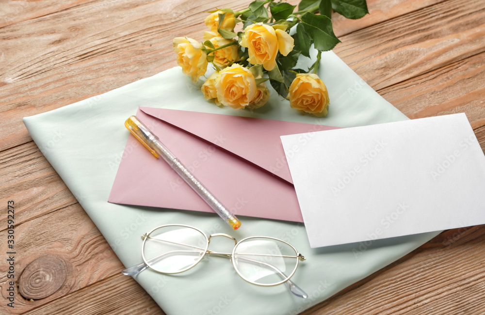 Composition with empty greeting card and envelope on wooden background