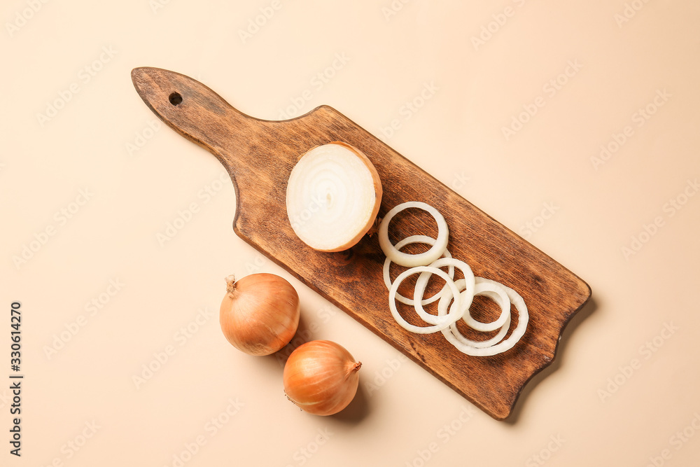 Cutting board with fresh raw onion on color background