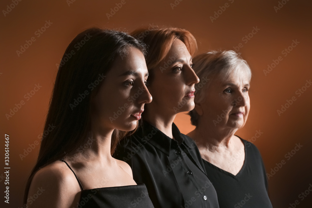 Portrait of mature woman with her adult daughter and mother on dark color background