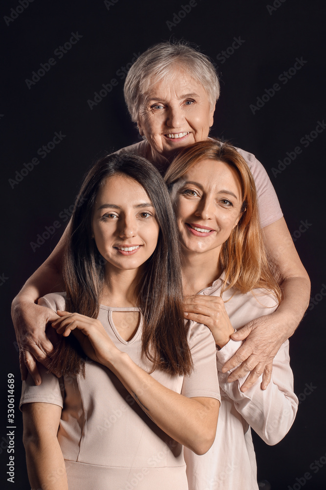 Portrait of mature woman with her adult daughter and mother on dark background