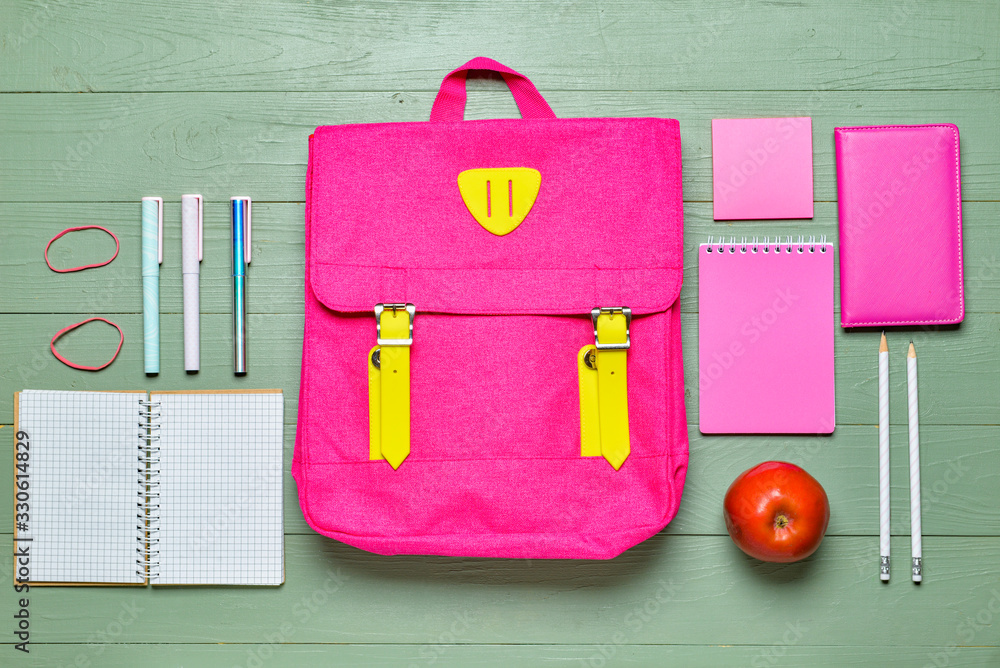 School backpack and stationery on wooden background