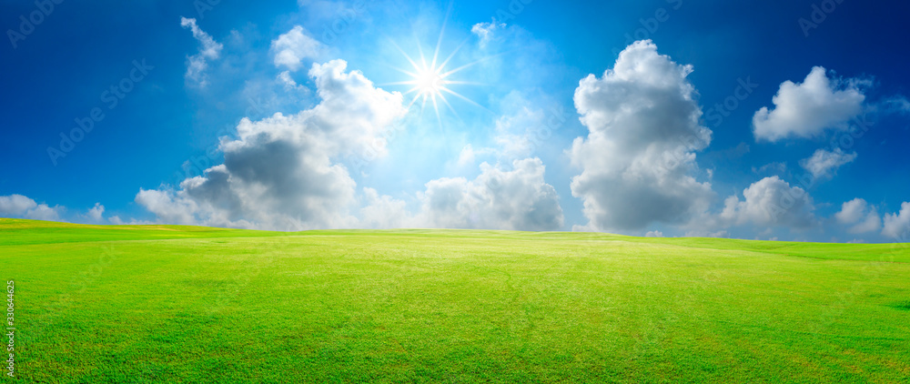 Green grass field and blue sky with white clouds,panoramic view.