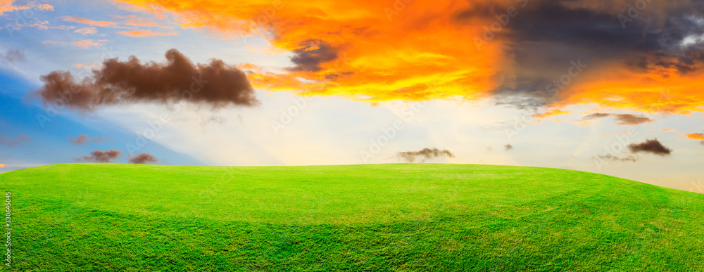 Green grass field and colorful sky clouds at sunset,panoramic view.