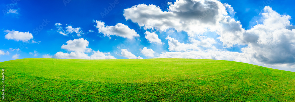 Green grass field and blue sky with white clouds,panoramic view.