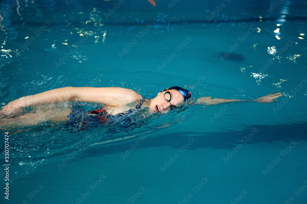 Female swimmer swimming on her back in pool