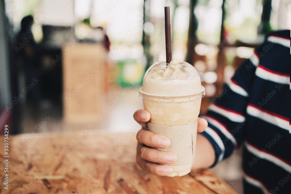 woman hand holding coffee in plastic cup in shop