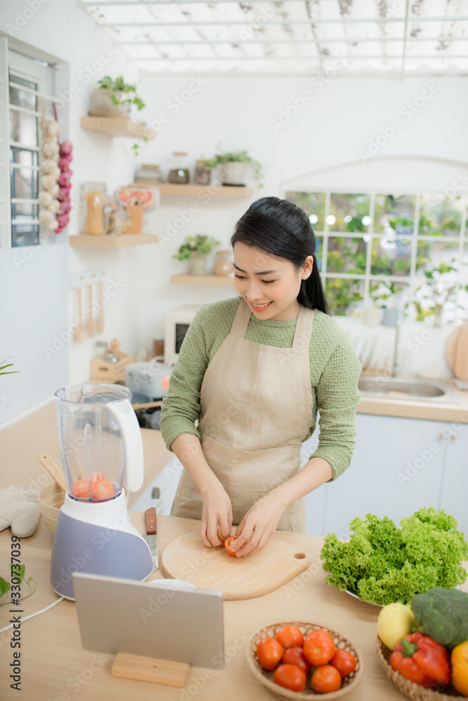 年轻女士站在厨房里用平板电脑烹饪蔬菜沙拉的画面