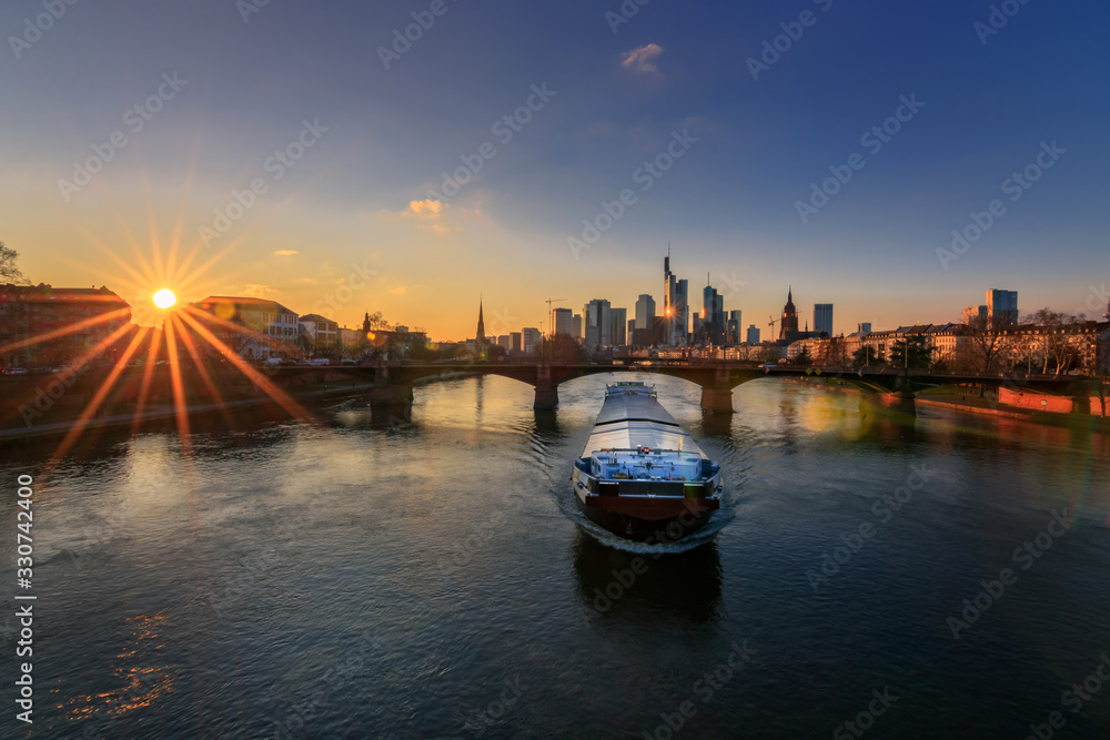 Frankfurt skyline, view over the river Main towards the skyline at sunset with a ship on the water