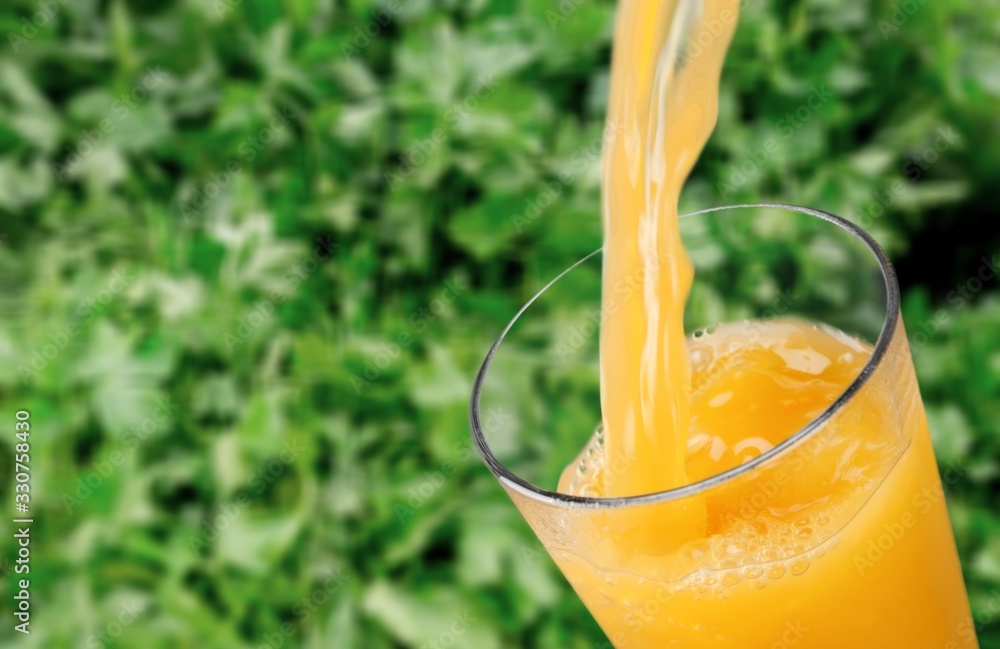 Orange juice pouring in glass on background