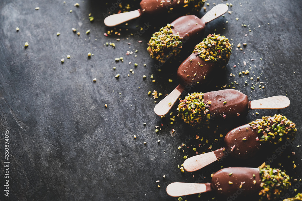 Ice cream popsicle pattern. Chocolate glazed ice cream pops with pistachio icing over dark backgroun