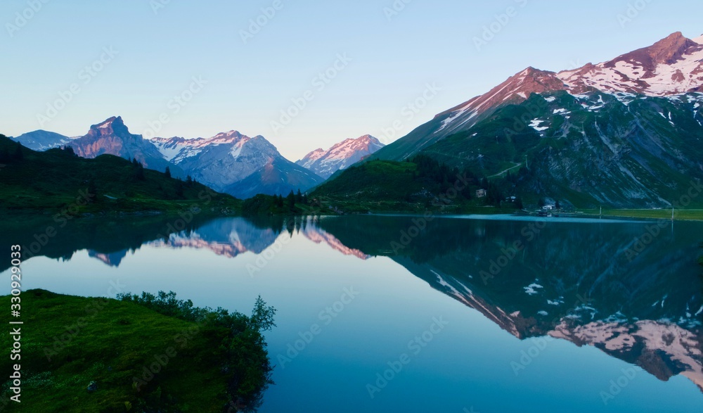 Landscape with mountain lake at sunrise – snowy mountain reflected in water