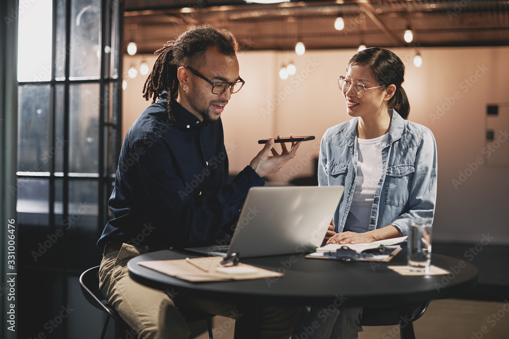 Smiling young businesspeople talking with a client over the phon