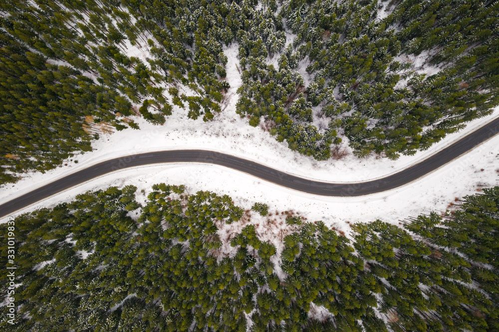 飞越冬季山脉，蜿蜒曲折的道路和白雪皑皑的森林。俯视图。景观照片