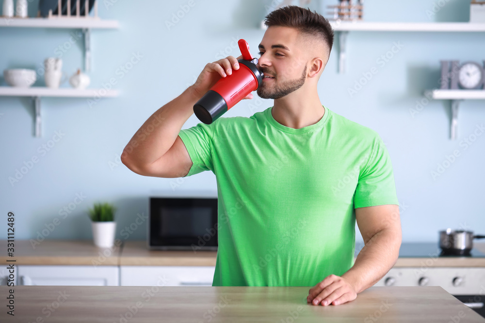 Sporty man with protein shake in kitchen