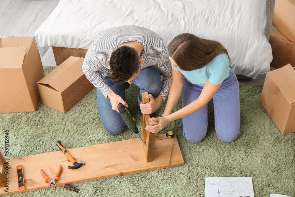 Young couple assembling furniture at home