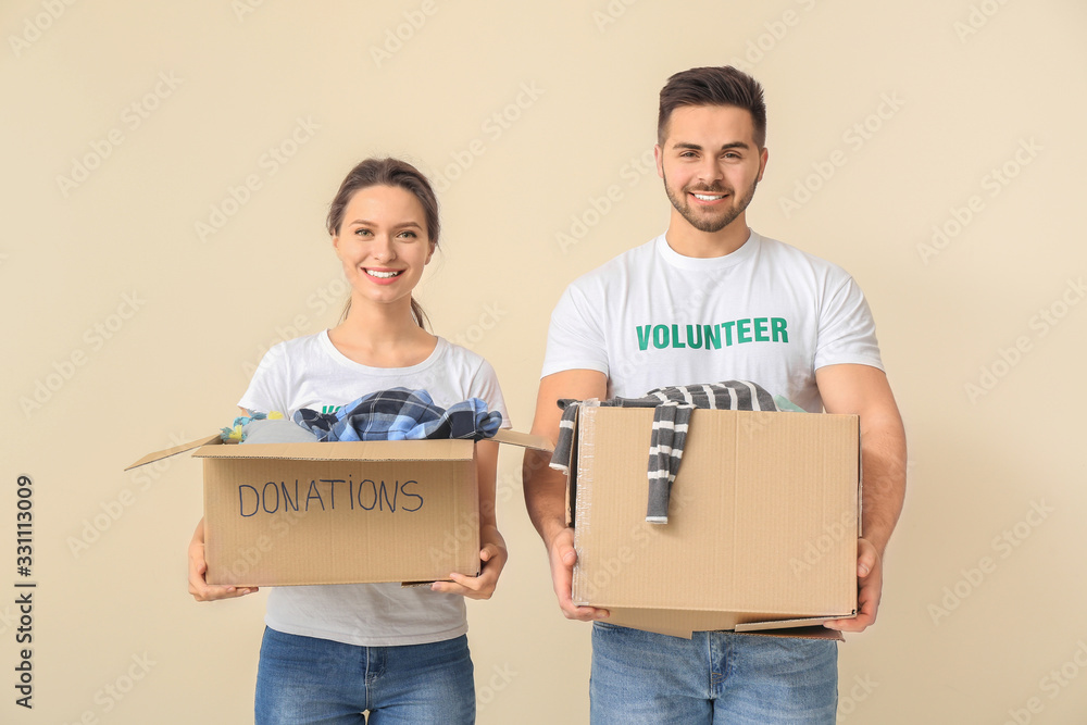 Volunteers with donations for poor people on color background