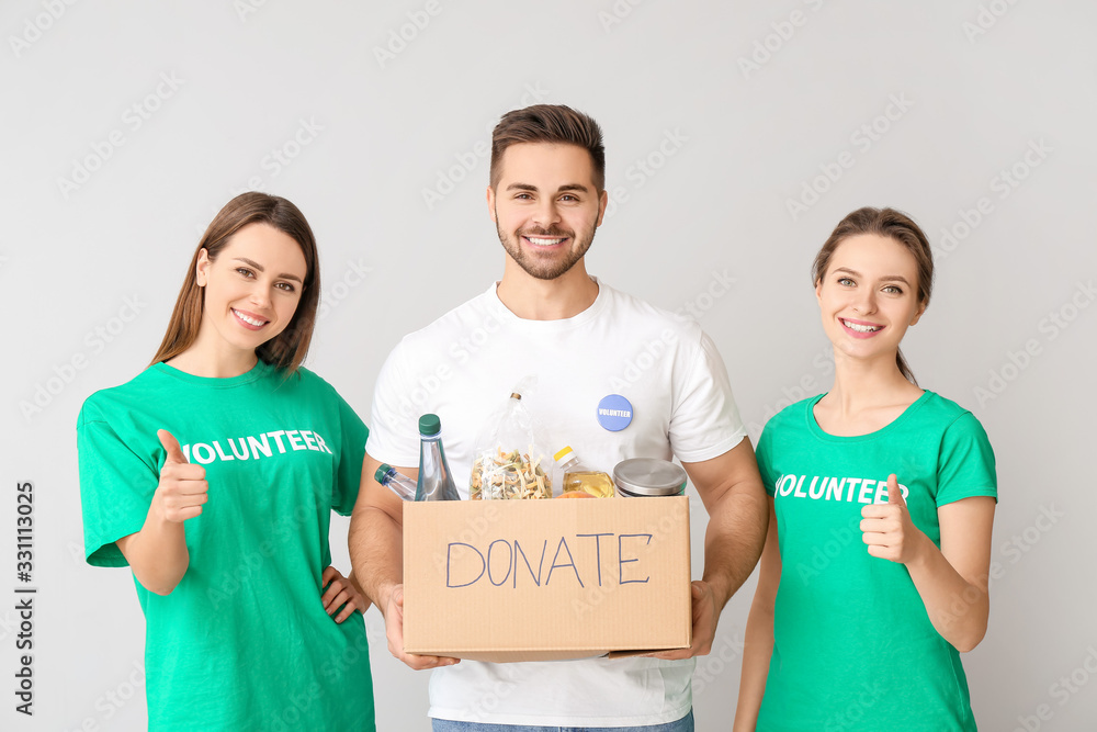 Volunteers with donations for poor people on light background