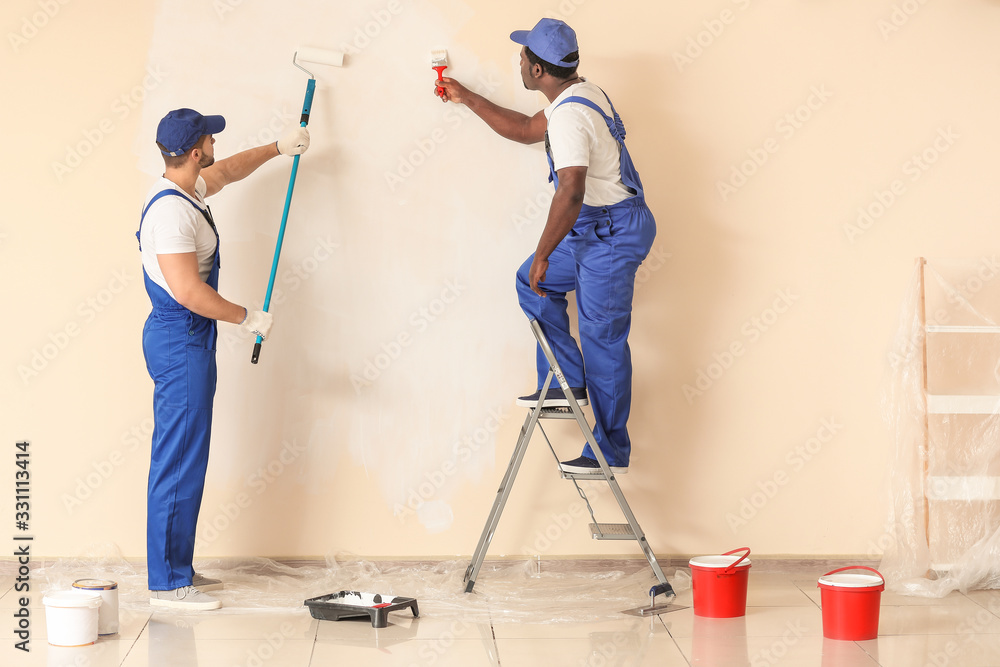 Male painters doing repair in room