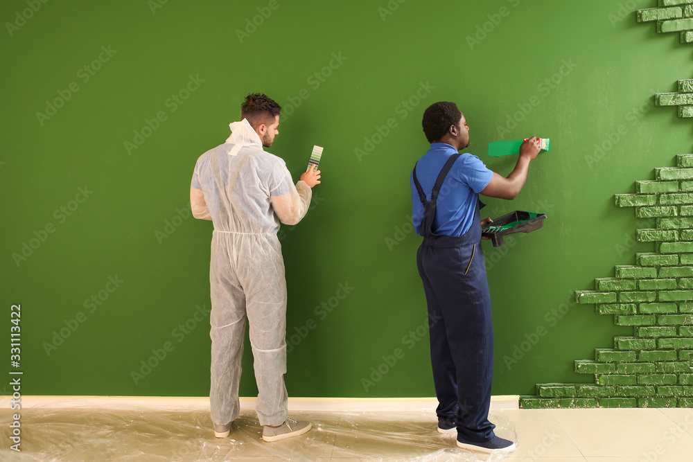 Male painters doing repair in room